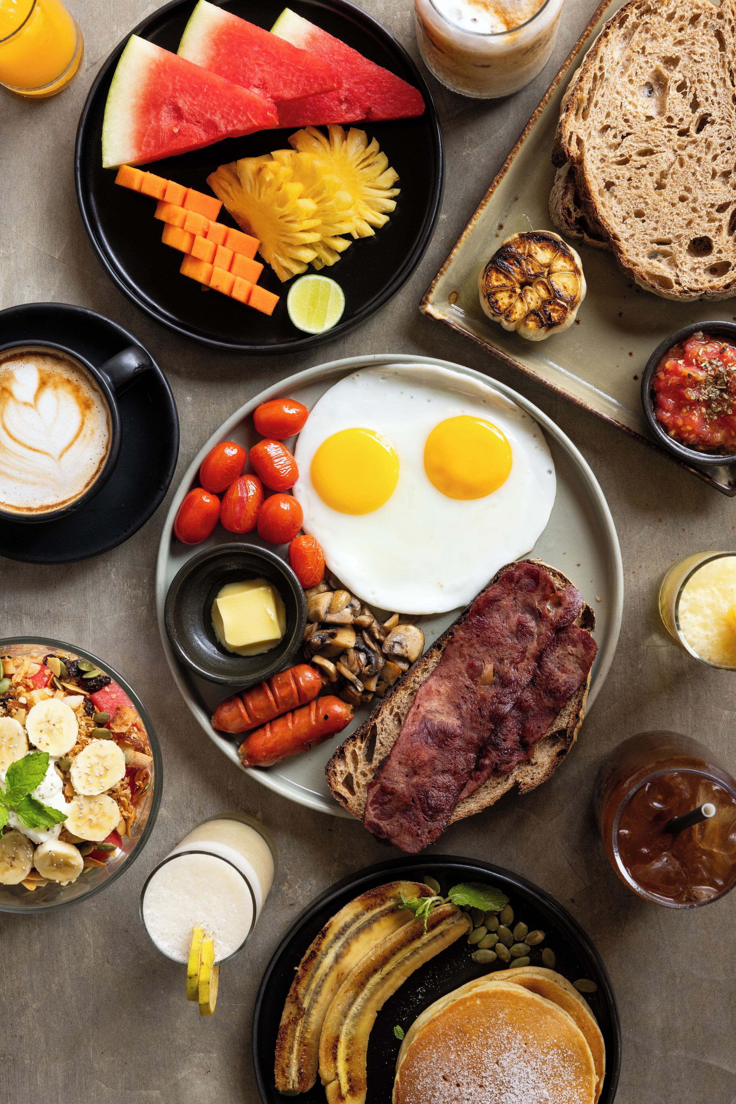 A breakfast spread with eggs, toast, tomatoes, and various fruits.