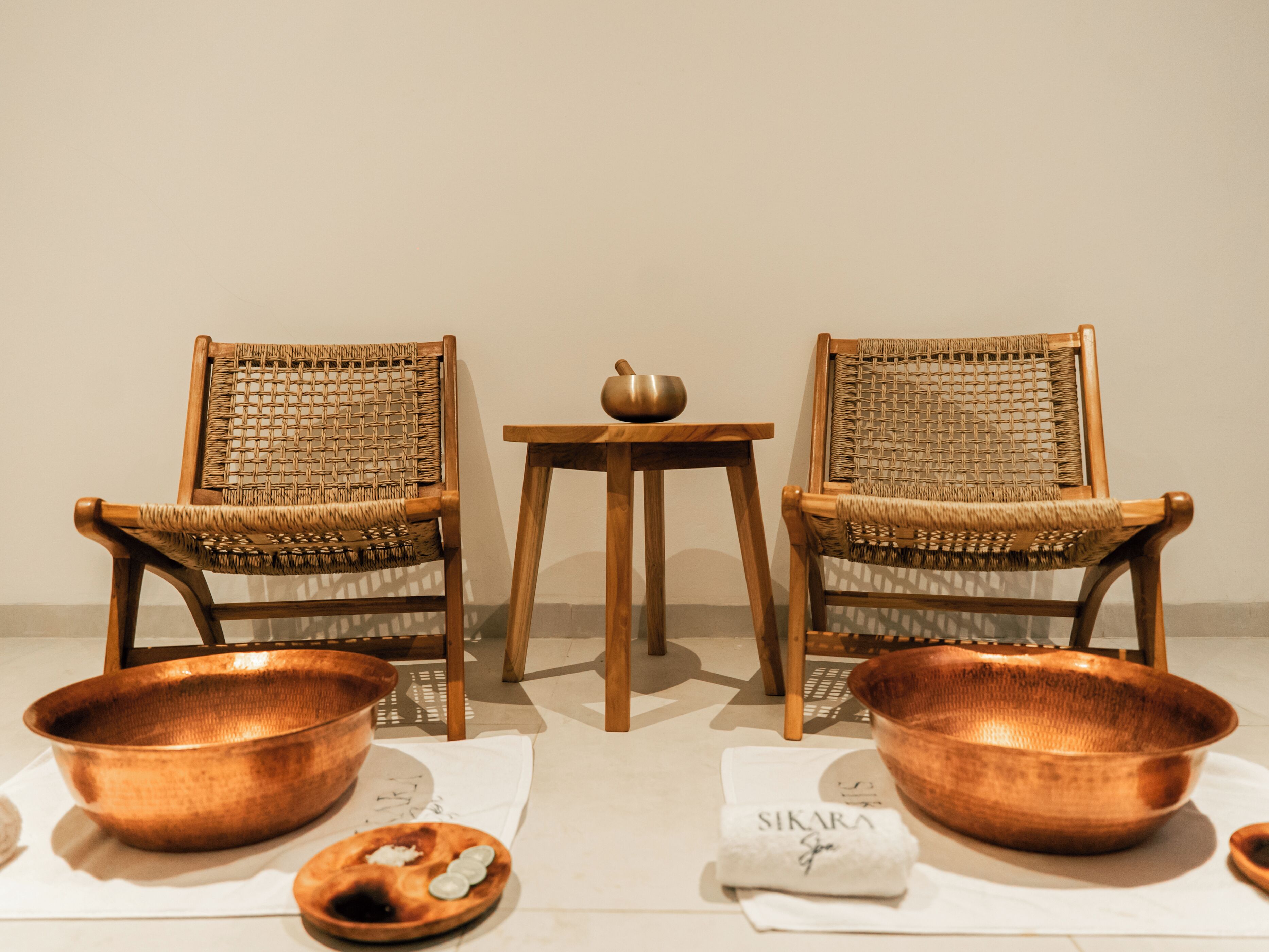 Two wicker chairs with copper bowls and a small table between them.
