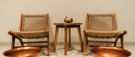 Two wicker chairs with copper bowls and a small table between them.