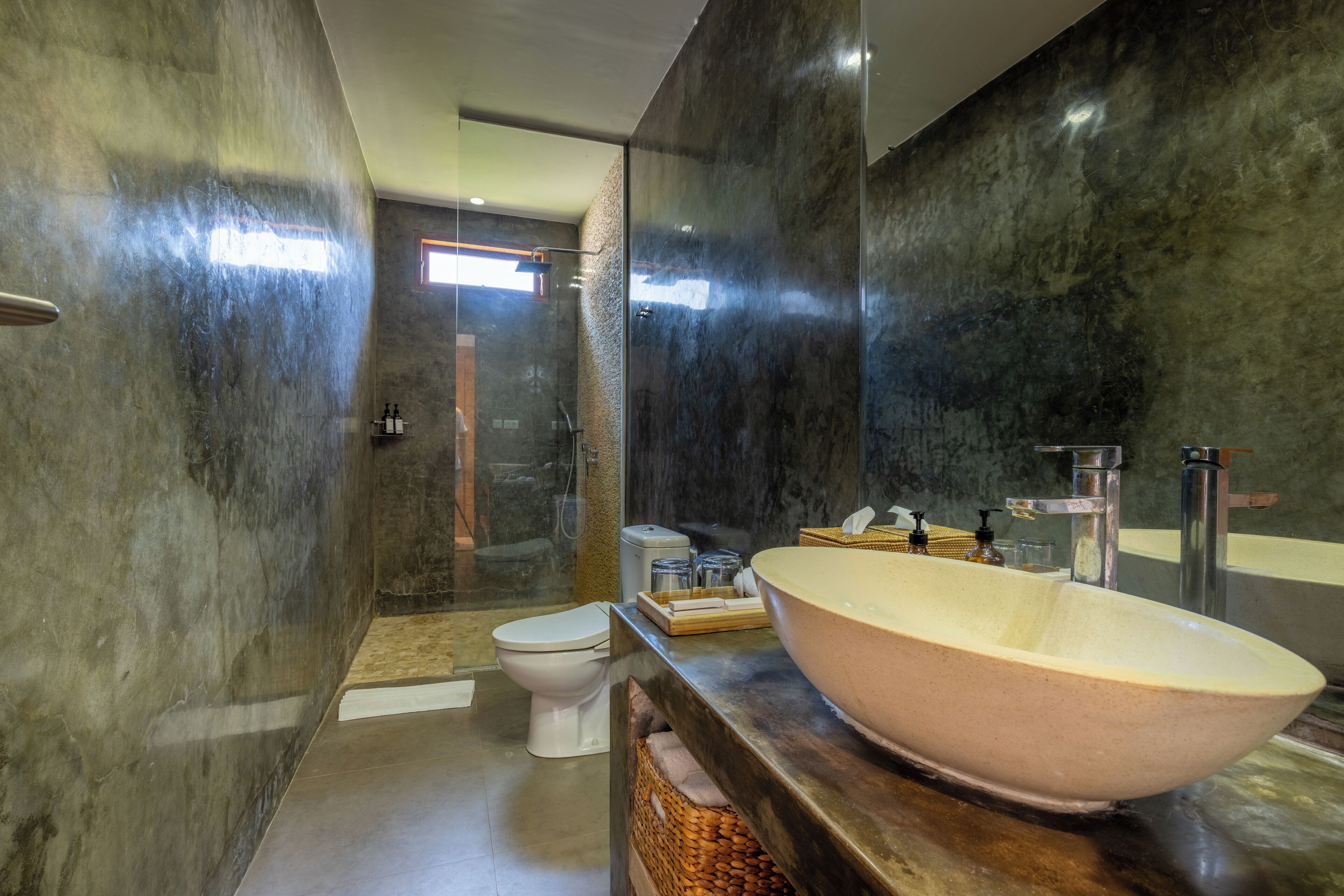 A modern bathroom with a large vessel sink, a toilet, and a shower area.