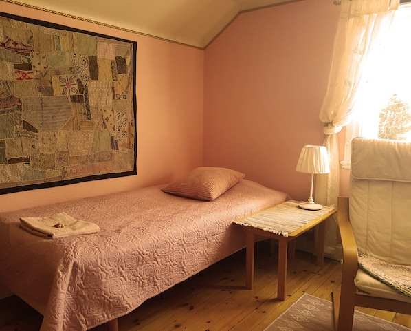 Un lit simple avec une couverture, une table de chevet avec une lampe et une décoration murale.