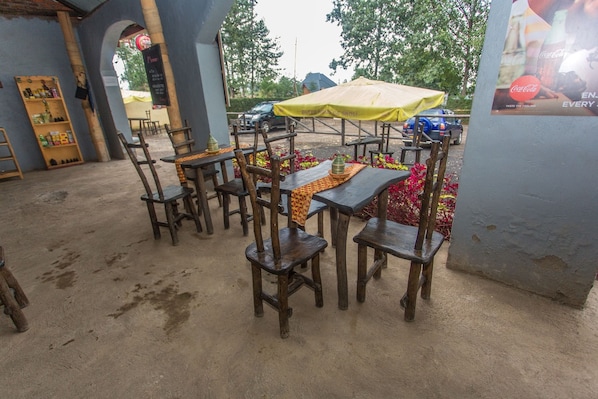 An outdoor seating area with wooden tables and chairs, a yellow umbrella, and a Coca-Cola advertisement.