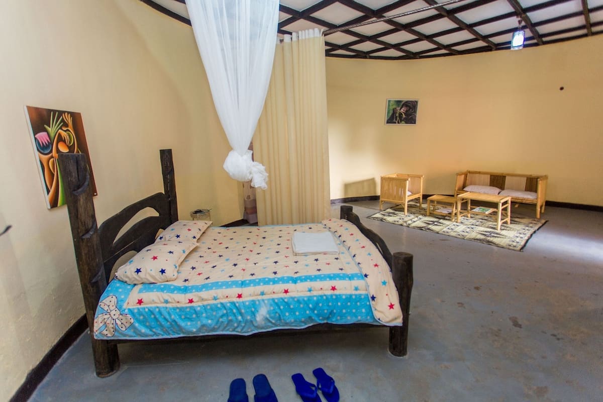 A bedroom with a bed, a wooden chair, a small table, and a curtain.