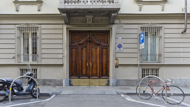 A building with a large wooden door, a parking sign, and a bicycle parked in front. - B&B Tohouse Deluxe (Turin)