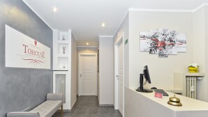 A hotel reception area with a modern design, including a reception desk, a bench, and a wall-mounted artwork. - B&B Tohouse Deluxe (Turin)