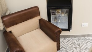 A chair with brown leather armrests and a beige seat, positioned next to a refrigerator with a patterned tile backsplash. - B&B Tohouse Deluxe (Turin)