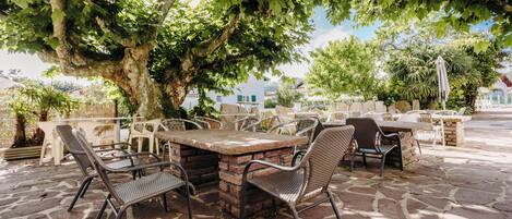 An outdoor patio with stone flooring, a brick table, and wicker chairs.