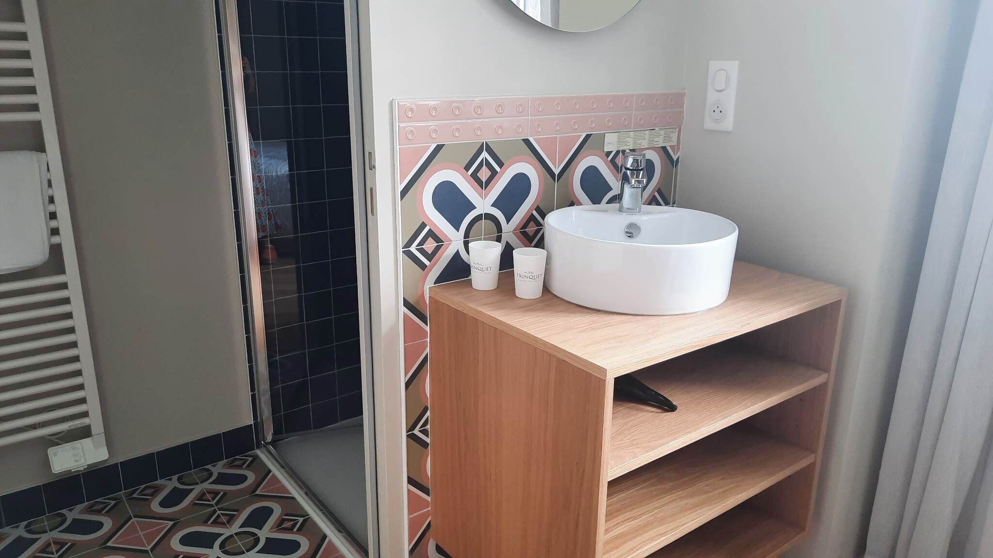 A bathroom with a white sink, a mirror above it, and a patterned tile backsplash.