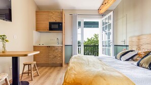 A compact bedroom with a bed, a small kitchenette, and a balcony with a view. - Hotel Trinquet (Saint-Pee-sur-Nivelle)