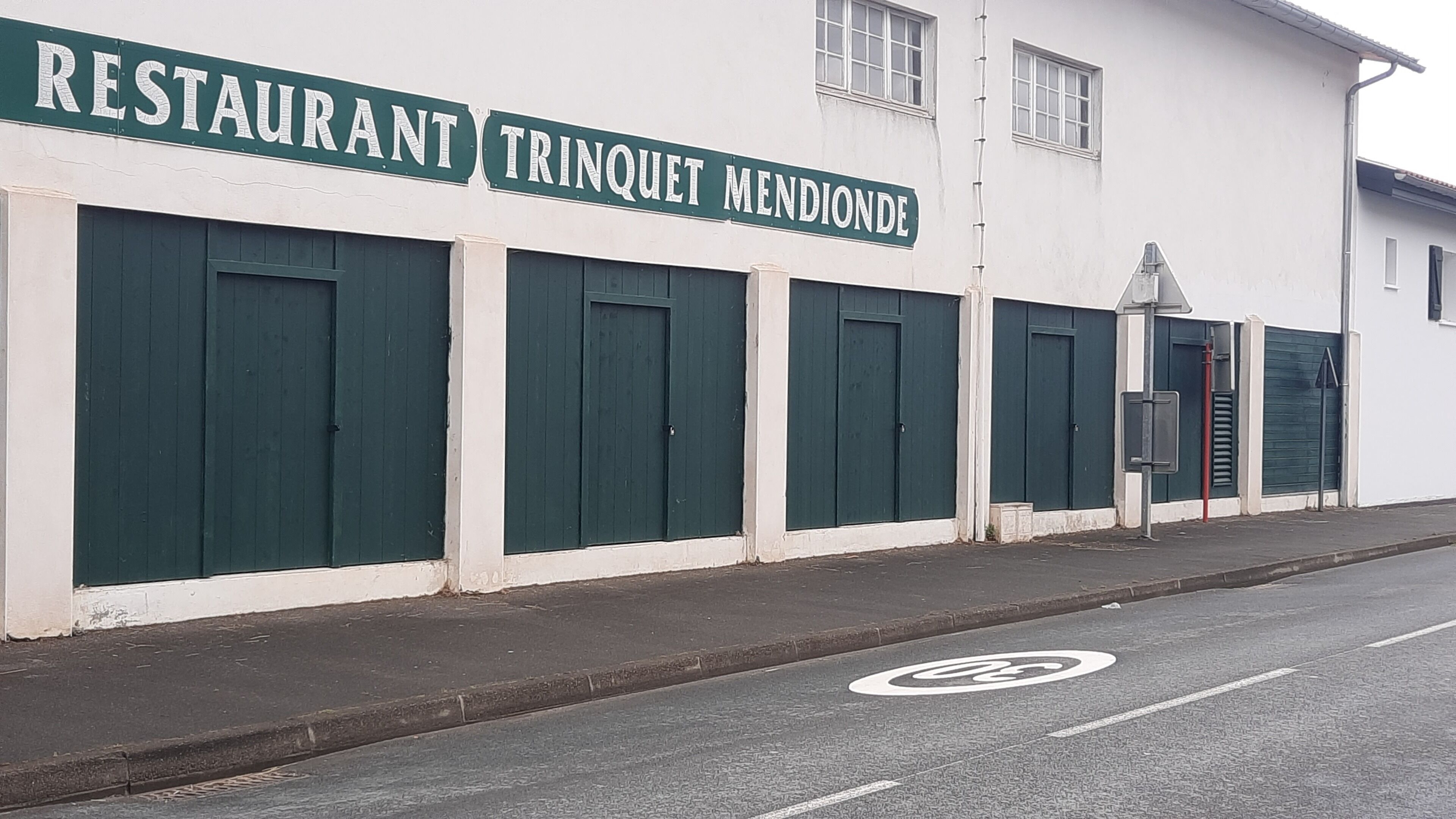 A building with a sign reading "RESTAURANT TRINQUET MENDIONE".