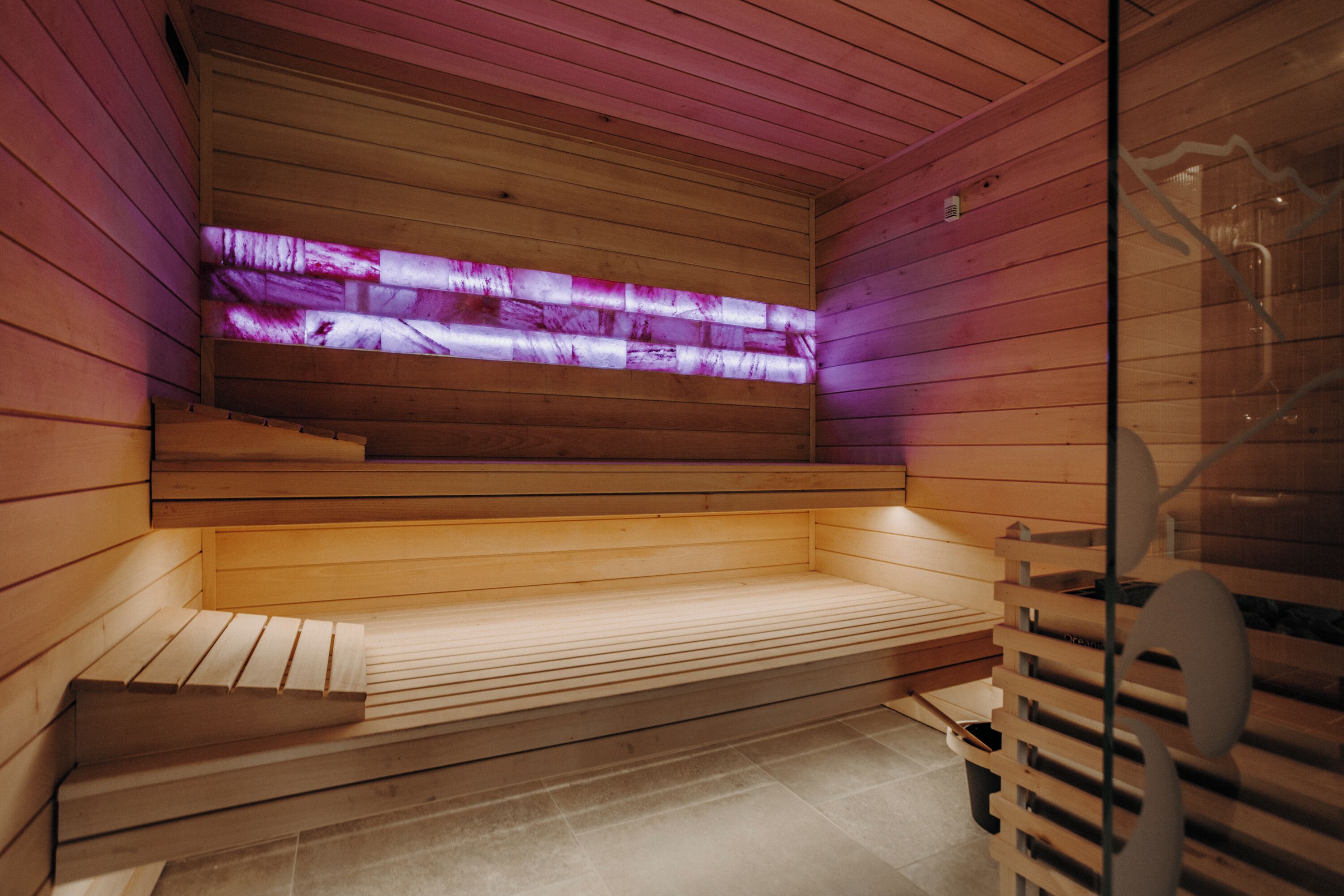Una sauna de madera con bancos y una pared de vidrio.