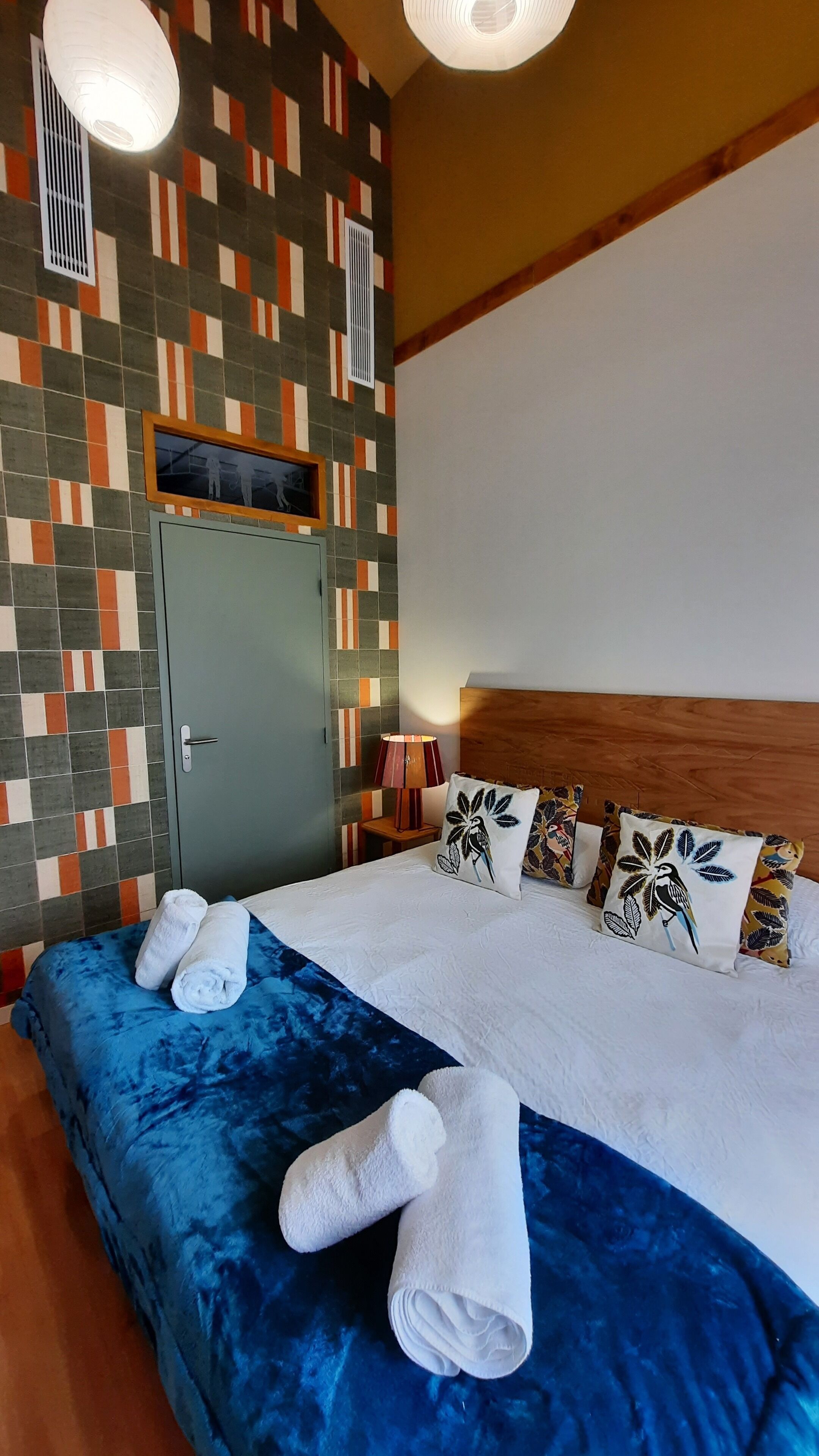 A hotel room with a bed, a nightstand, a lamp, and a wall with a geometric pattern.