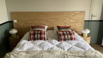 A bed with a wooden headboard, two patterned pillows, and two bedside lamps on wooden stands.