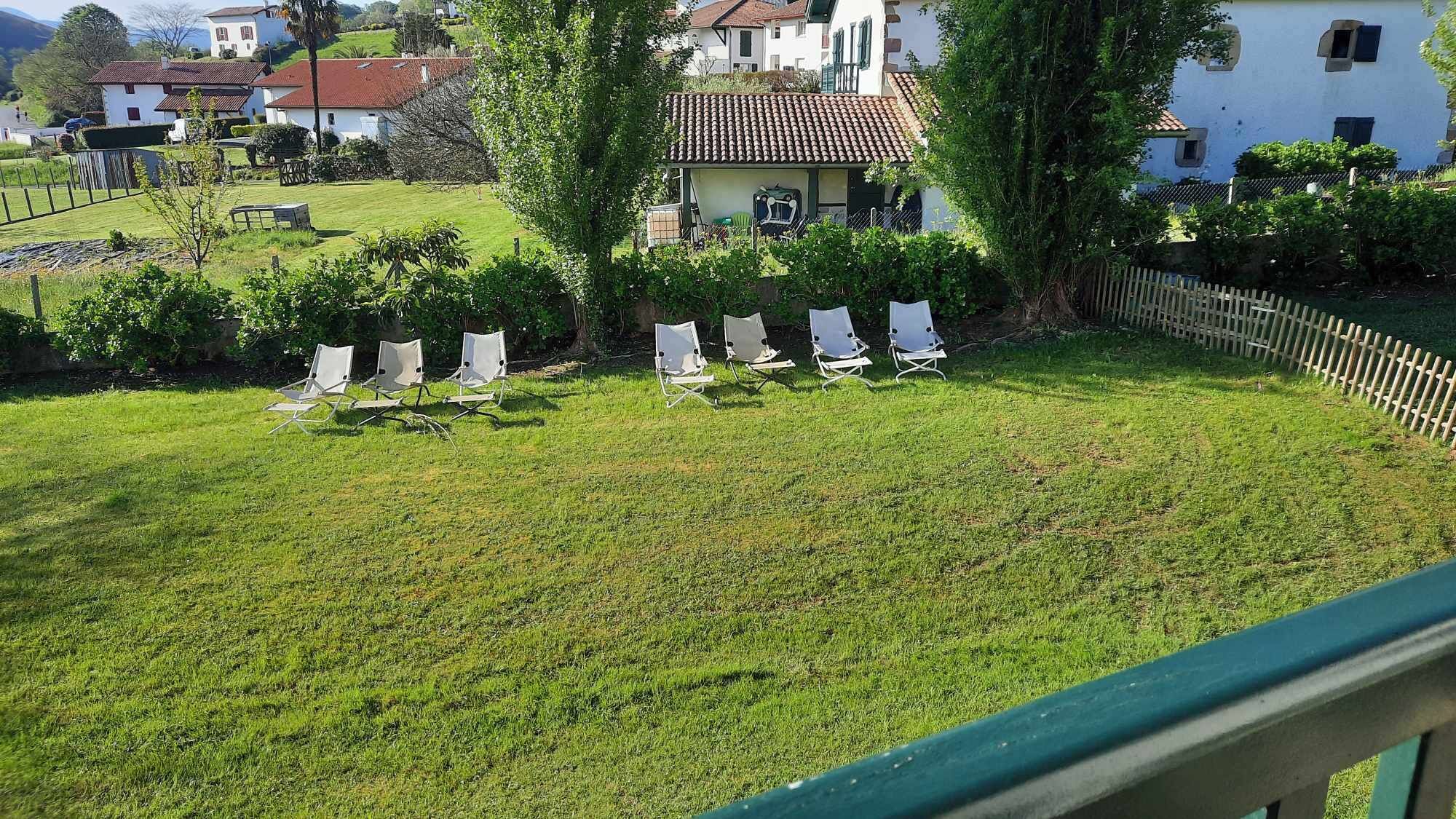 Een gazon met daaraan verschillende witte tuinmeubels, rijend gepositioneerd.