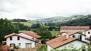 A rural village with white houses and red roofs, surrounded by green hills and trees. - Hotel Trinquet (Saint-Pee-sur-Nivelle)