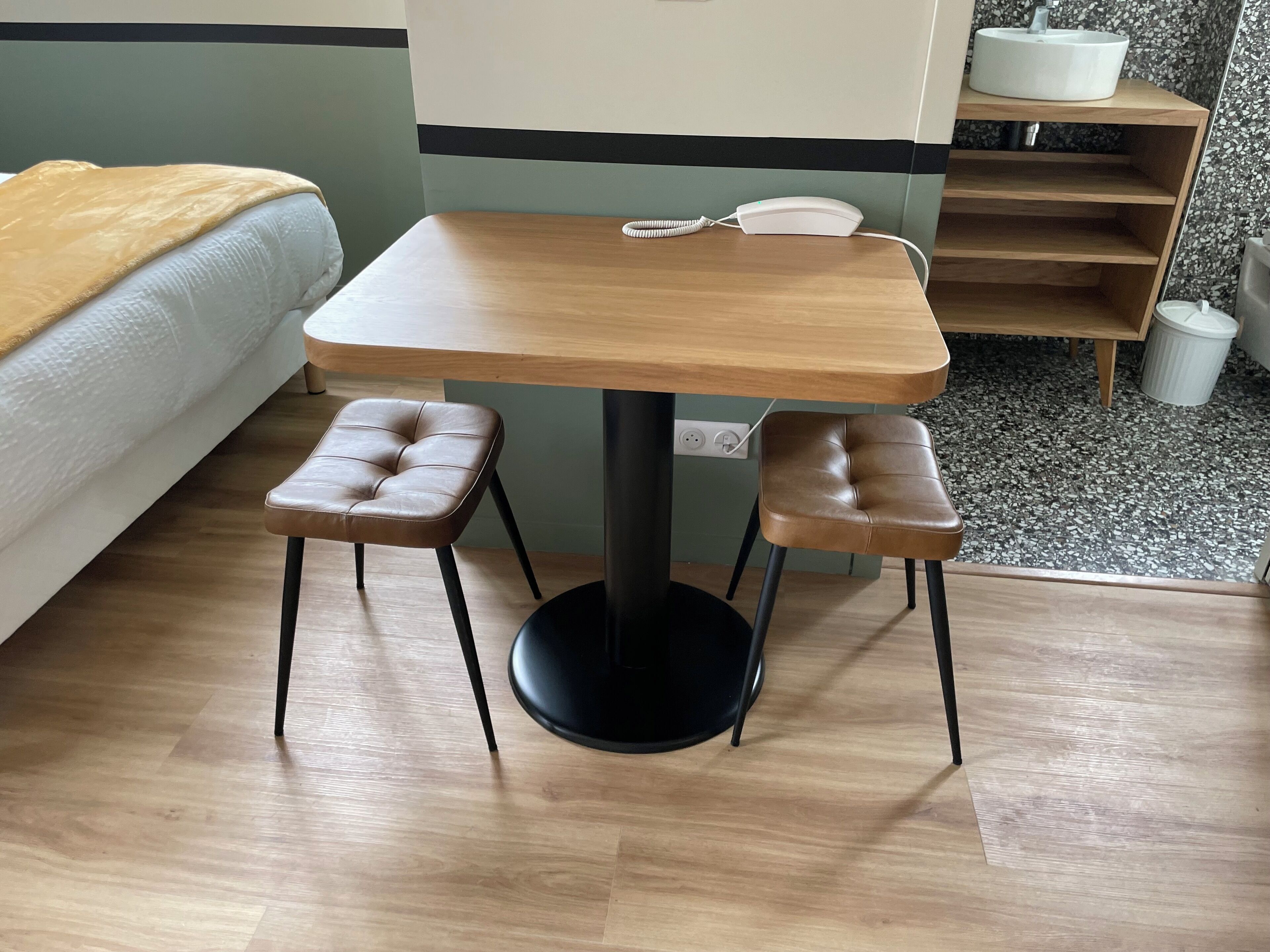 A small, modern room with a wooden table and two leather stools.
