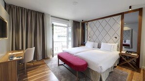 A hotel room with a bed, a desk, a chair, a TV, and a window with curtains. - Hotel Silken Palacio Uribarren (Lekeitio)