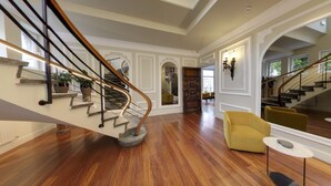 A spacious interior with a wooden staircase, yellow armchairs, and a dining area. - Hotel Silken Palacio Uribarren (Lekeitio)