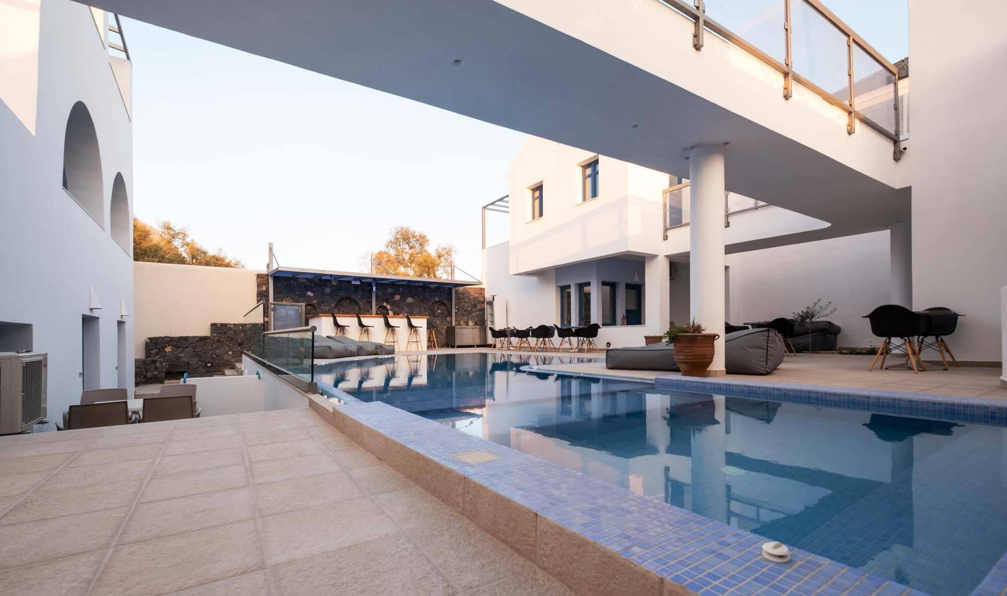 A modern outdoor swimming pool with a stone wall and seating area.