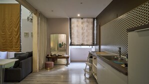 Cuina moderna amb un rentaplat, taulell i zona de menjador amb sofà i taula.