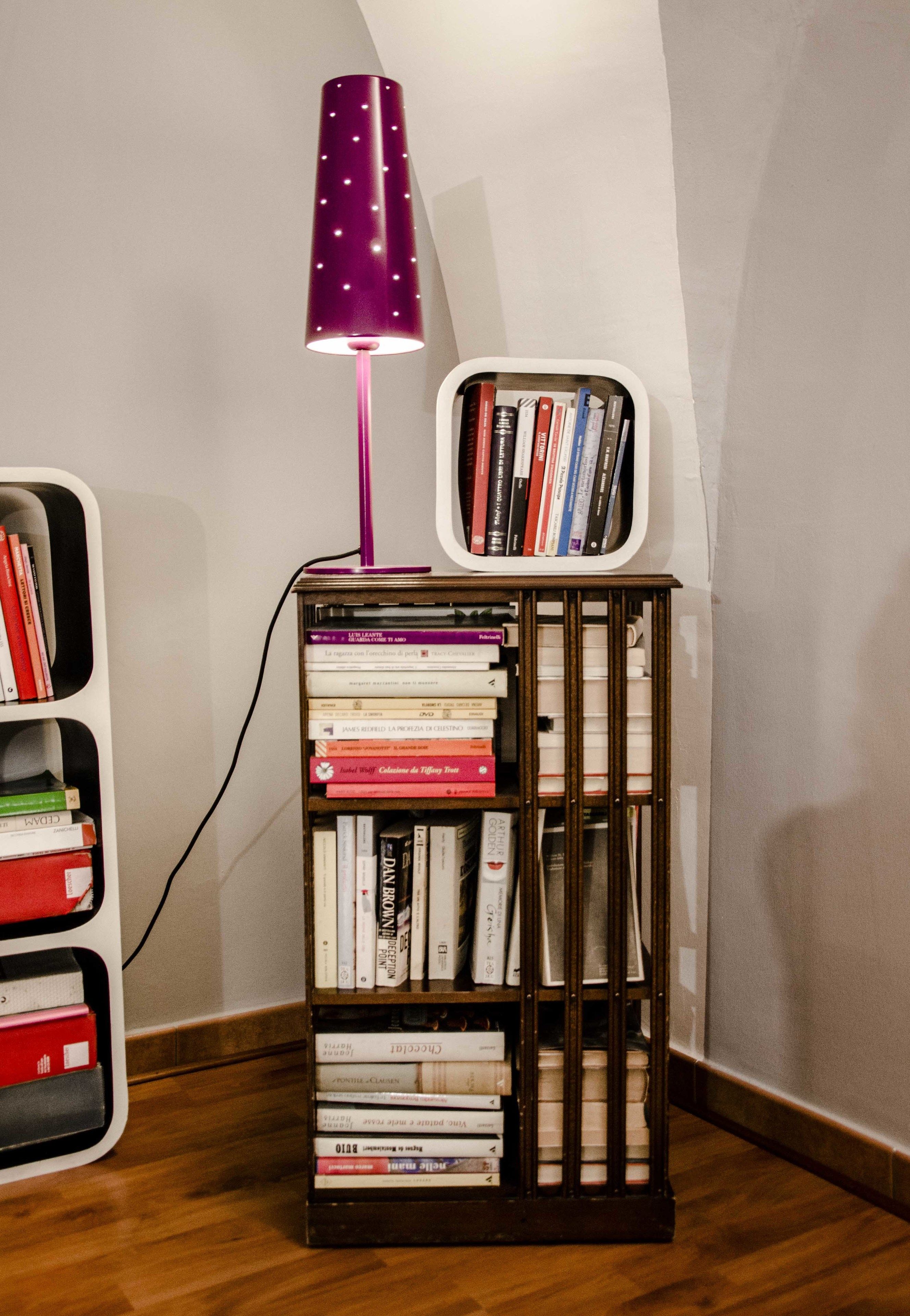 Een boekenplank met boeken en een paarse lamp.