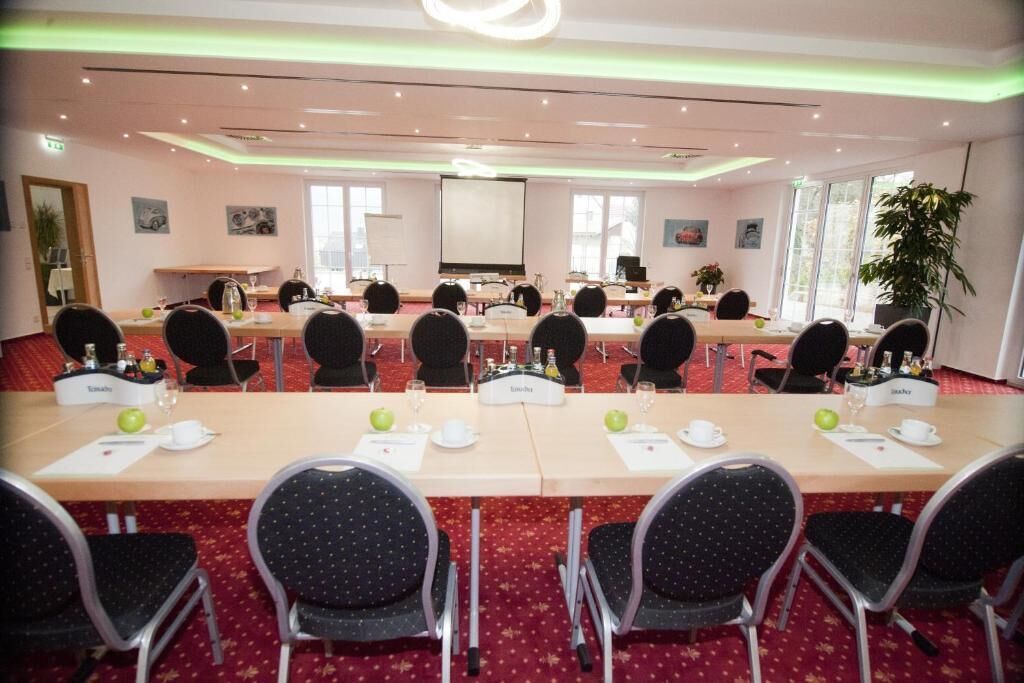 A conference room with multiple tables, chairs, and a projector screen.