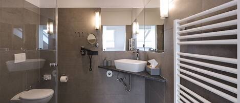 A modern bathroom with a glass shower enclosure, a toilet, a sink with a vanity, and a towel rack.