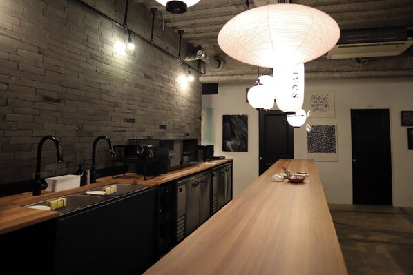 A modern kitchen with a brick wall, wooden countertop, and a long wooden table. - Waves Nakameguro (Tokyo)