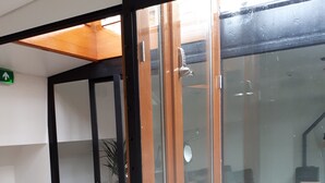 A room with a sliding glass door leading to a balcony, a desk with a computer, and a potted plant. - Rooms on Water (Rotterdam)