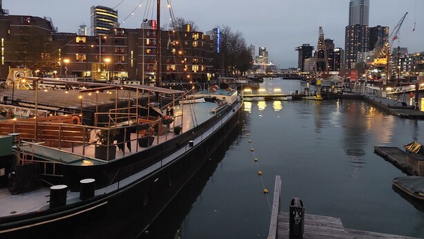 A canal with boats docked, a bridge, and buildings in the background. - Rooms on Water (Rotterdam)