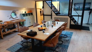 A modern kitchen with a dining area, featuring a wooden table, chairs, and a variety of kitchen appliances. - Rooms on Water (Rotterdam)