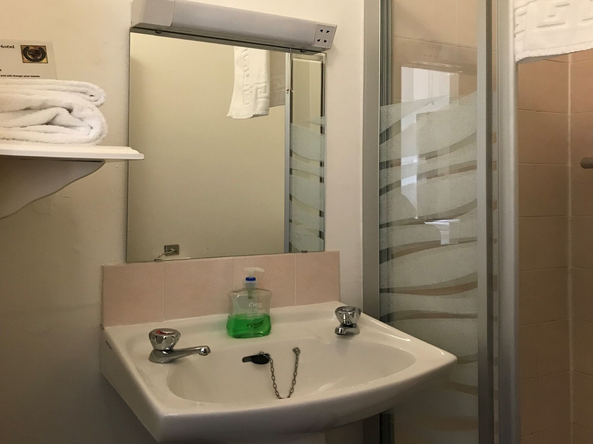 Een badkamer met een wit wastafel, een spiegel en een douchecabine van glas.
