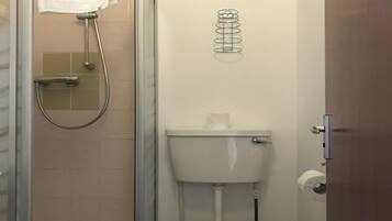 Un baño pequeño y funcional con inodoro, cabina de ducha y una toalla colgada en la pared.