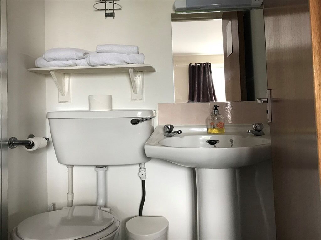 A bathroom with a toilet, sink, and a towel rack.