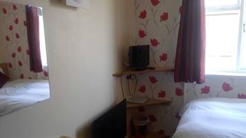 A hotel room with two beds, a TV on a shelf, a mirror, and a window with curtains.