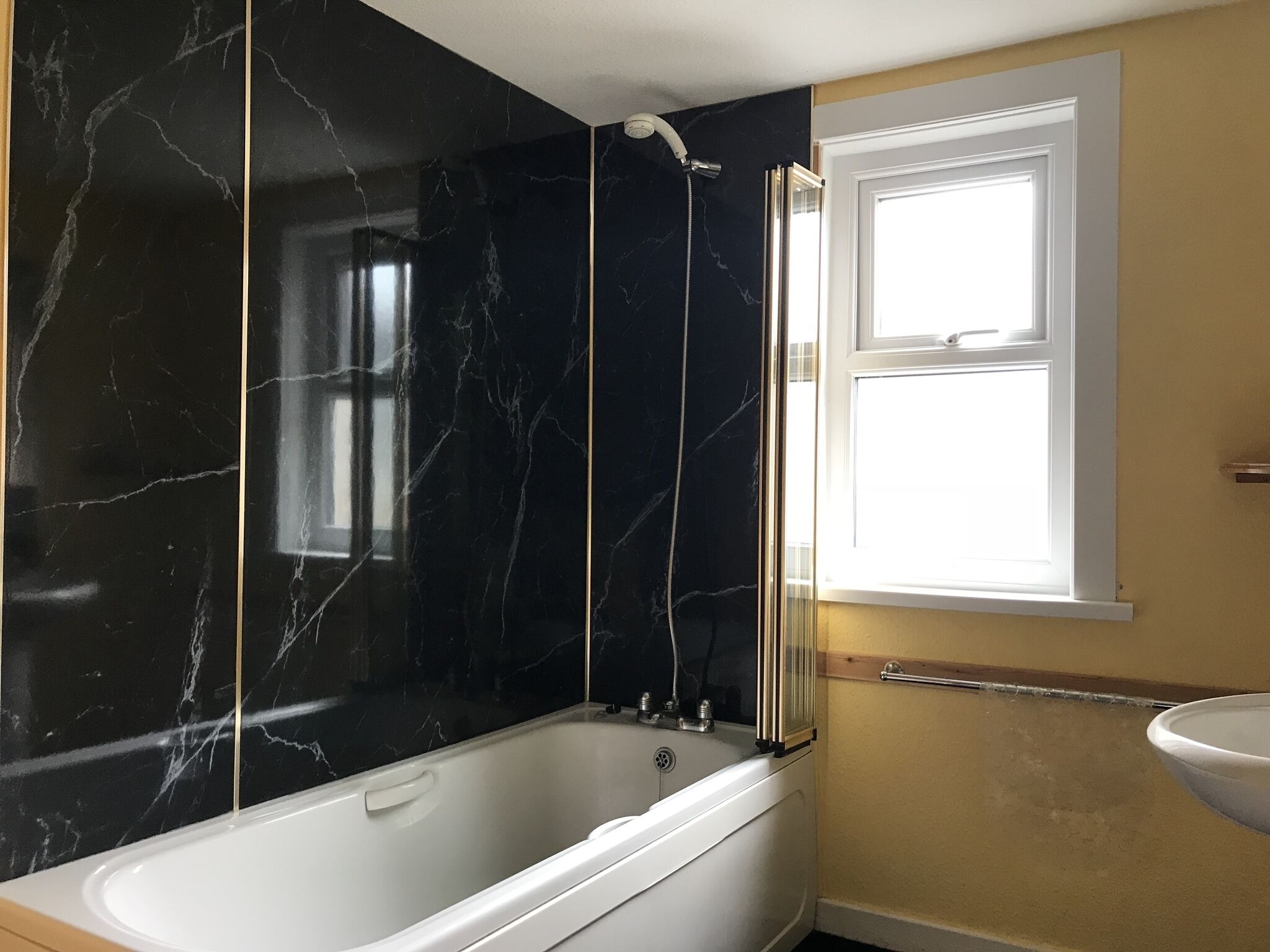 Un baño con bañera, ducha y ventana.