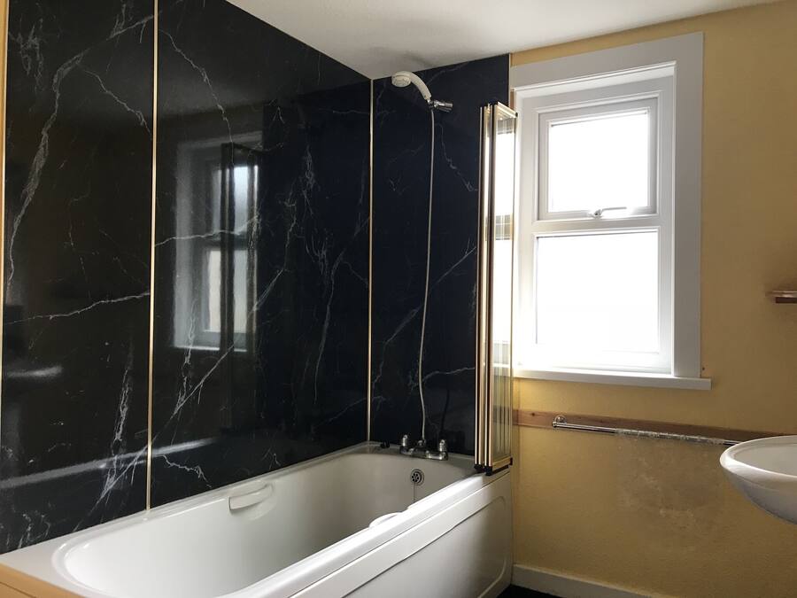 Un baño con bañera, ducha y ventana.