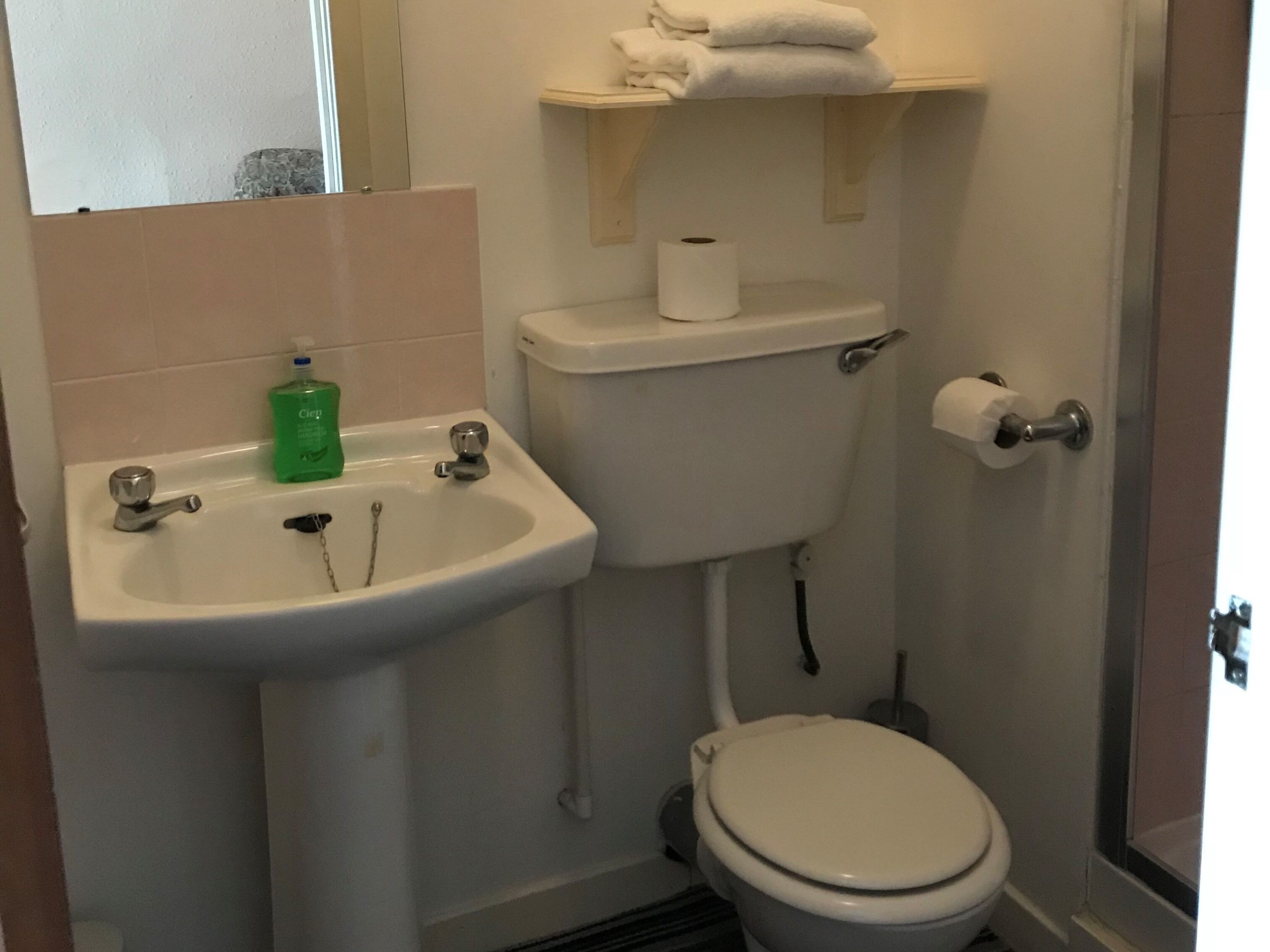 Ein Badezimmer mit Waschbecken, Toilette und einem Ablagebereich mit Handtüchern.