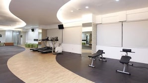 Ein modernes Fitnessstudio mit Cardiogeräten, Gewichtbänken und einem geschwungenen Holzboden.