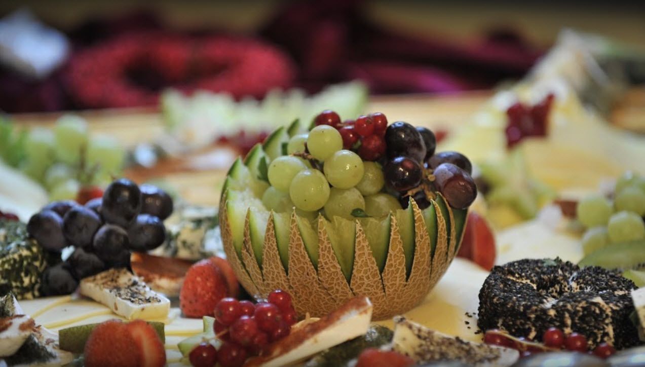 Eine Platte mit Obst und Käse, darunter Trauben, Beeren und verschiedene Käsesorten.