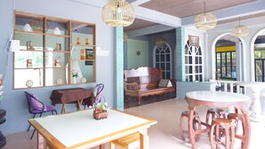 A room with a wooden table, purple chairs, a bench, and wicker pendant lights. - Thansila Resort (Ranong)