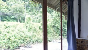 A room with a view of a rocky stream and dense greenery outside. - Thansila Resort (Ranong)