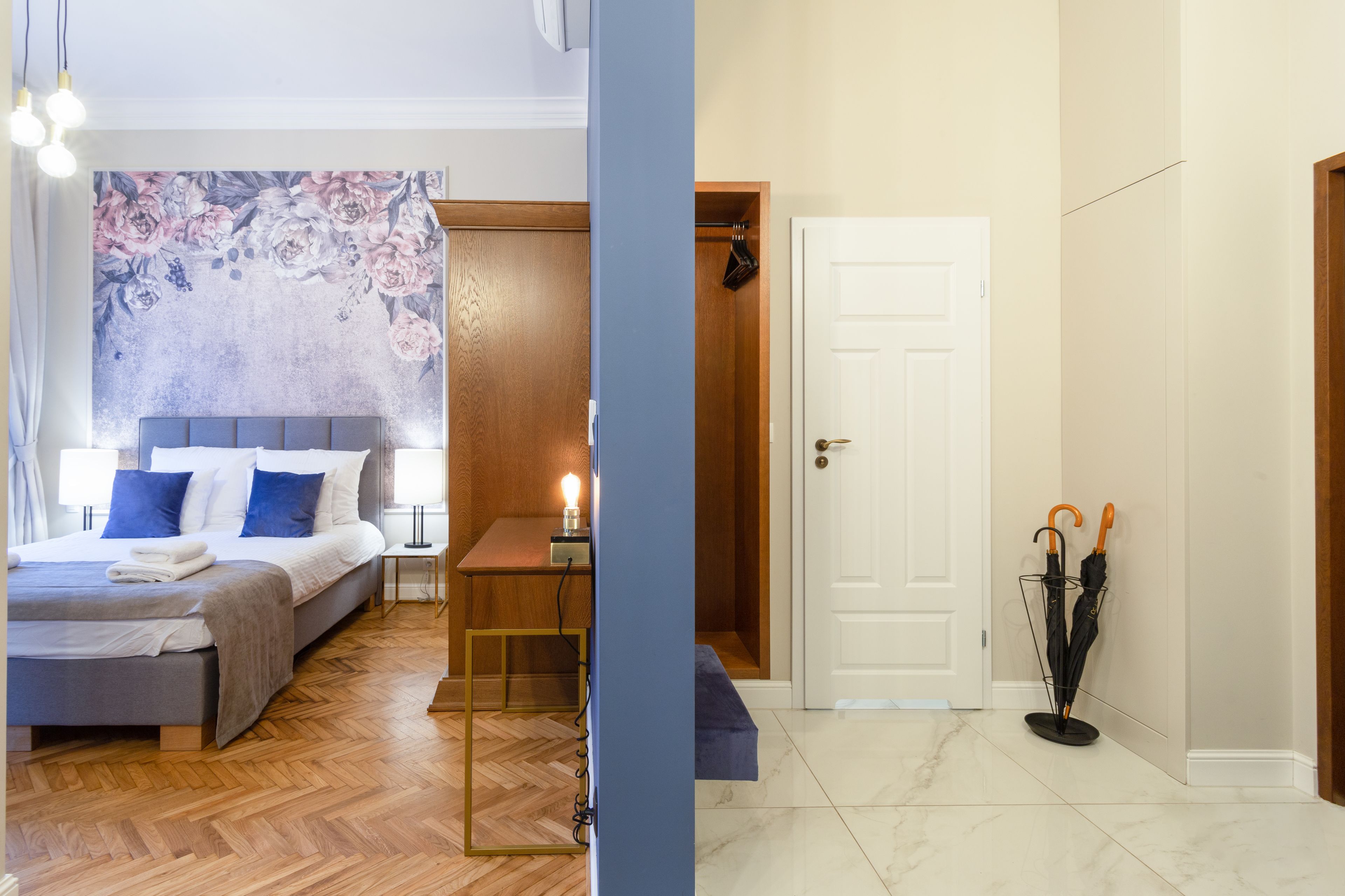 A bedroom with a bed, bedside table, and a wall with a floral mural.