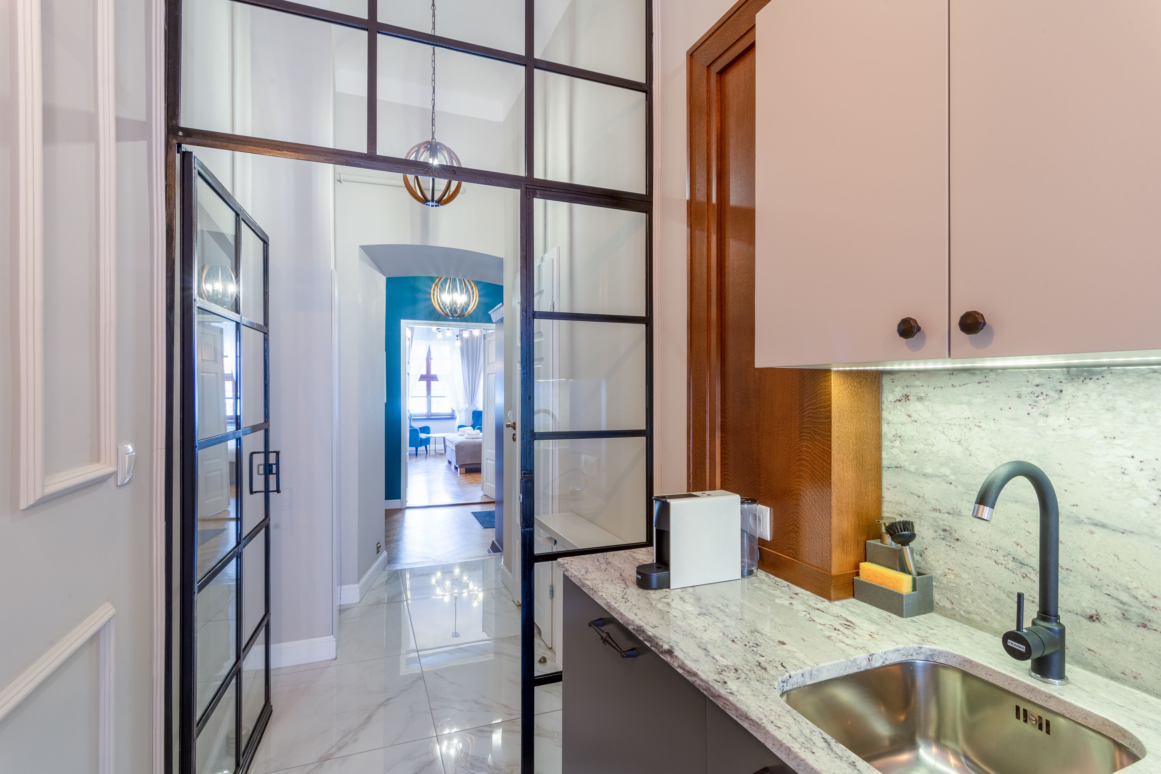 A modern kitchen with a stainless steel sink, a coffee machine, and a marble countertop.