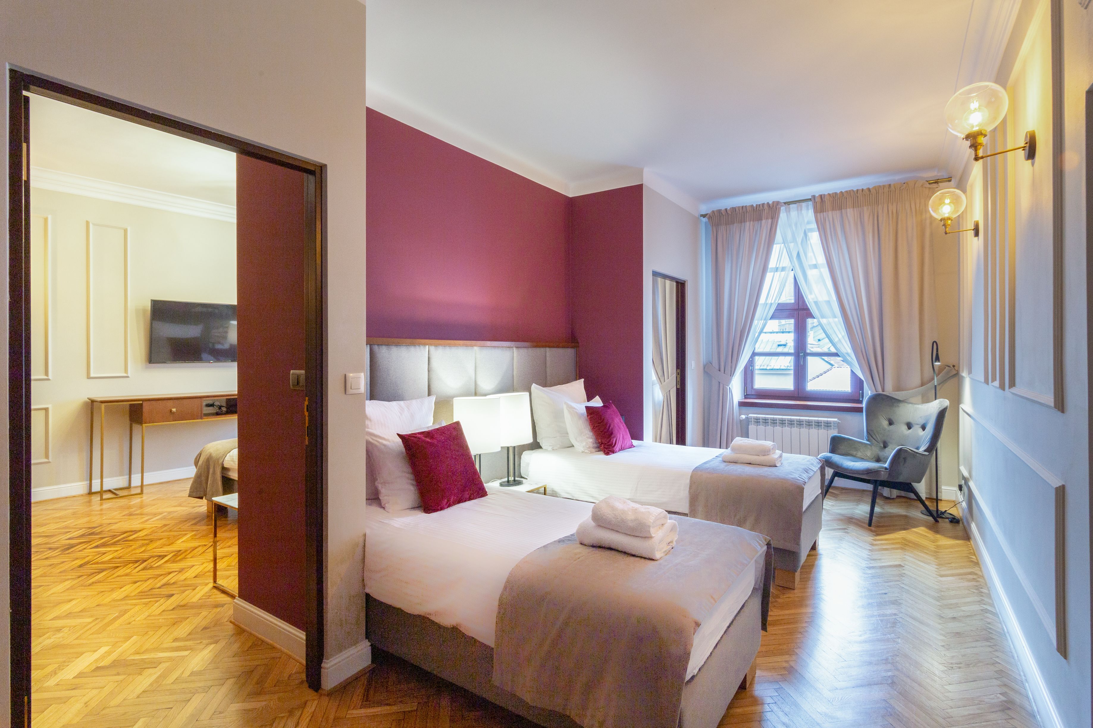 A hotel room with two beds, a desk, a chair, and a television.