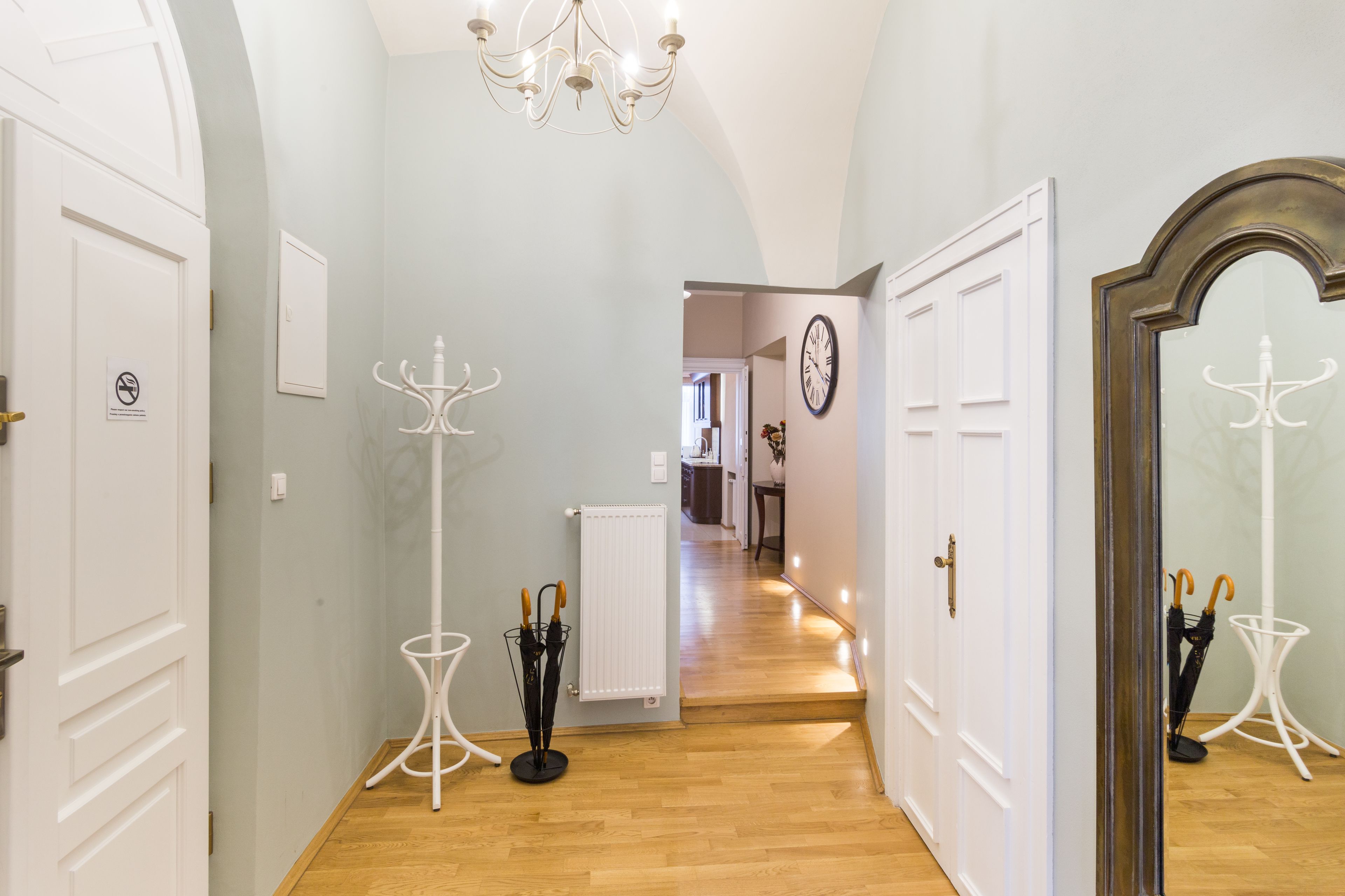 Un couloir avec des portes blanches, un radiateur et un lustre.