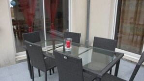 Une table à plateau en verre, quatre chaises, une bougie et un verre d’eau.