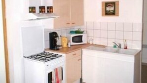 Une cuisine compacte équipée d’une cuisinière à gaz, d’un four à micro-ondes et d’un petit évier.
