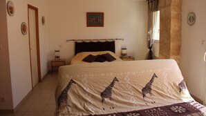 Une chambre à coucher avec un lit, une table de chevet, une lampe, un tableau au mur et une fenêtre avec des rideaux.