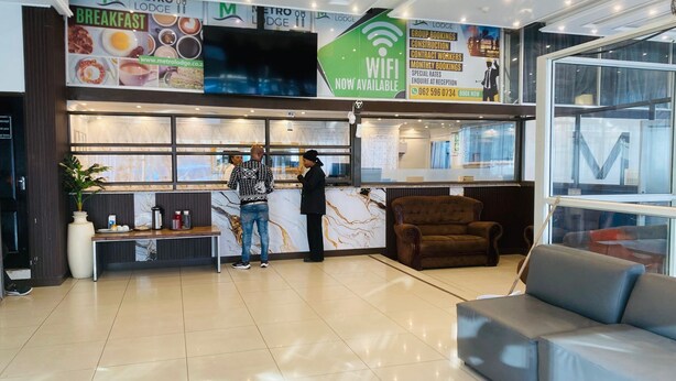 A hotel reception area with a marble counter, a sofa, and a large window. - Metro Lodge Beach (Durban)